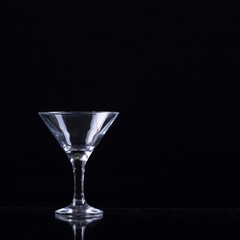 Empty glass of martini on black background