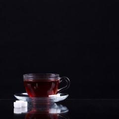 cup of black tea with slices of sugar on a black background