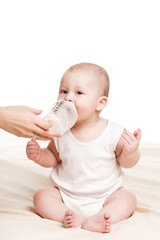 Cute baby with a bottle of milk on a beige blanket