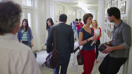 Mixed ethnicity group of students chatting in the hallway between classes