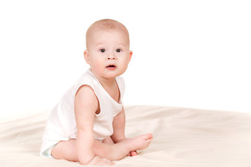 Charming babe is sitting on the bed, on a white background.