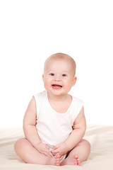 Charming babe is sitting on the bed, on a white background.