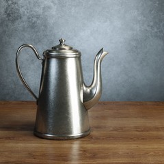 Retro coffee pot stand on wooden table behind grey wall