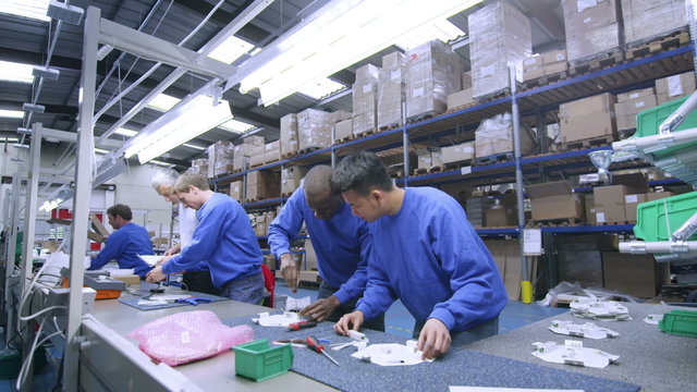 Male factory staff of mixed ethnicity working together on an assembly line
