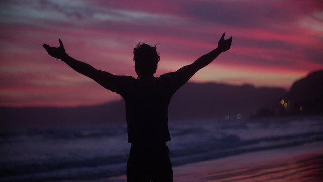Carefree guy expressing freedom at sunset on the beach
