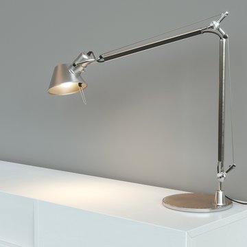 Metal desk lamp stand on white surface behind grey wall