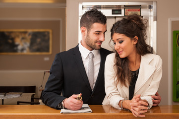 Young elegant happy couple at hotel reception with key room.