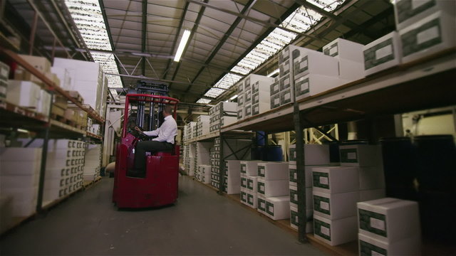 Forklift truck driver in a factory moving and loading goods