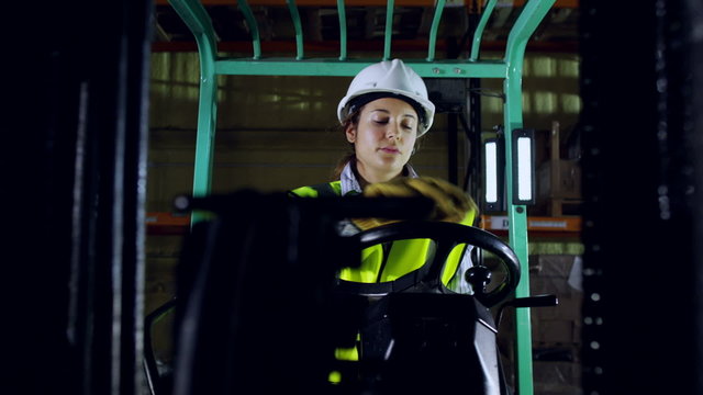 Close up of A female forklift truck driver in a factory at night