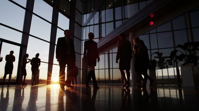 Business people walking through a modern office building at sunset