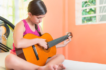 Fototapeta premium Hispanic teenage girl playing guitar at home