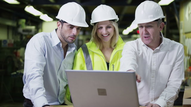 Workers in a warehouse with a laptop computer are preparing goods for delivery