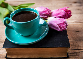 Cup of coffee on book with flowers.
