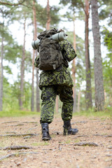 young soldier with backpack in forest