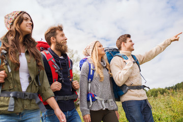 group of smiling friends with backpacks hiking