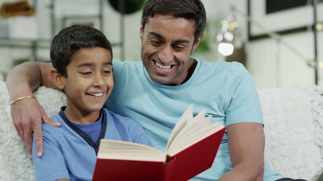 Father and son spending time together at home, reading a book