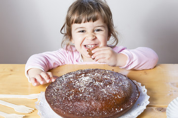 Adorable little girl eating a homemade chocolate cake