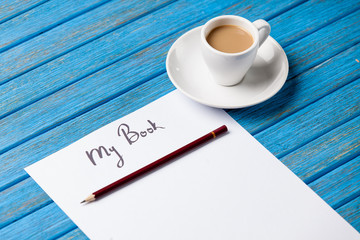 pencil and paper with inscription r cup of coffee