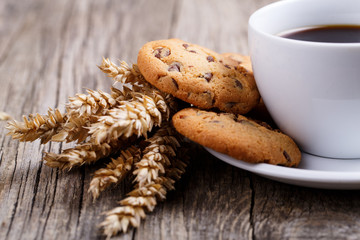 Cup of coffee with cookies and wheat on a table.