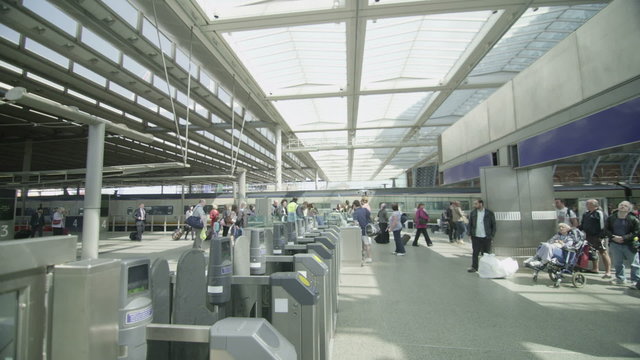 Travelers & commuters passing through ticket barrier at a London railway station