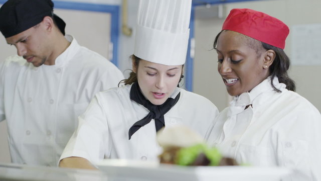 Happy team of chefs in a commercial kitchen, head chef gives instructions