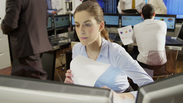 Young and ambitious female stock market trader hard at work in a busy office