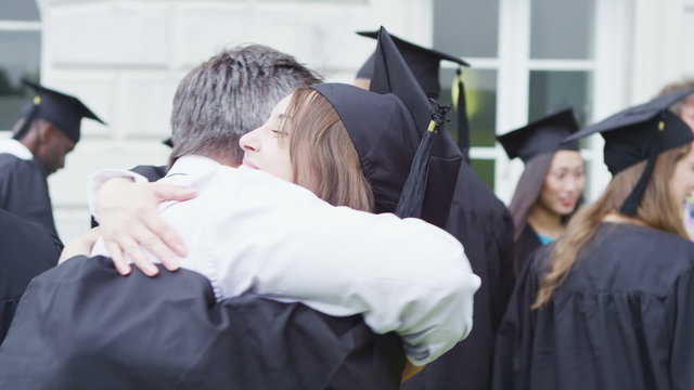Happy students on graduation day are hugged and congratulated by proud parents