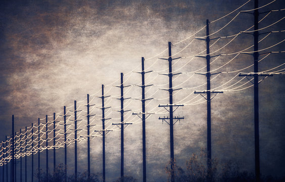 Cable lines at regular intervals reaching into the distance against a patch of clearing sky and cloud. 