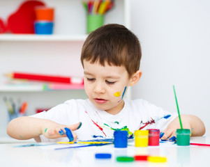 Little boy is playing with paints