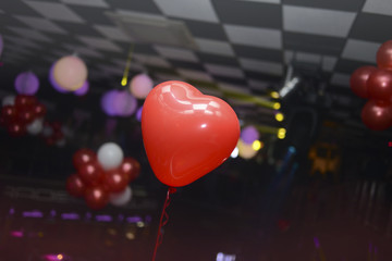 Vibrant red balloon shaped like a hearth, floating on a party