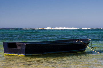 Vieja barca de madera vacía en las aguas cristalinas de las hermosas playas del Caribe en el Parque Nacional Tayrona en Colombia