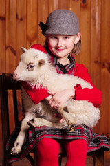 Young girl sitting on a chair holding a lamb in his arms
