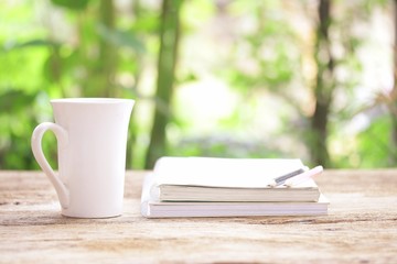 Notebook  and  white cup on wooden table