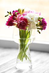Beautiful spring flowers in glass vase on windowsill background