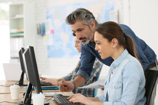 Trainer with student working on desktop computer