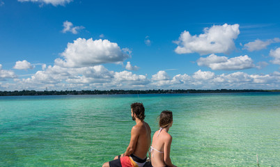 Beautiful couple in love looking at tranquil Bacalar lake. Rivie