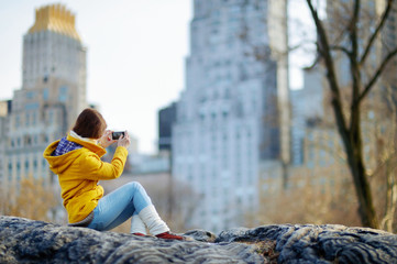 Beautiful young woman taking a photo of skyscapers - obrazy, fototapety, plakaty