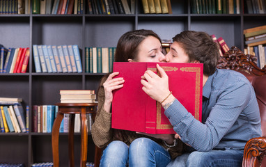 Young Sweet Couple Kissing Behind a Red Book