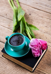 Cup of coffee on book with flowers.