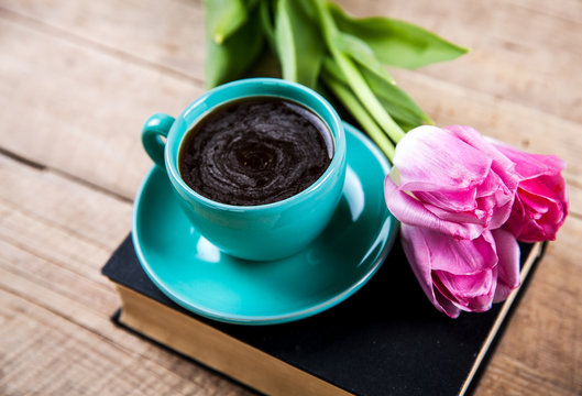 Cup of coffee on book with flowers.