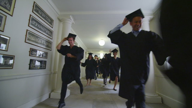 Excited group of students on graduation day running through the hallway