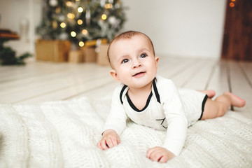 Fototapeta premium Baby boy in toddler on wooden floor over Xmas tree