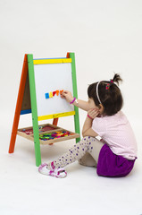 Musingly girl glues magnetic letters on white board isolated