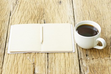 Black coffee and notebook on wooden table
