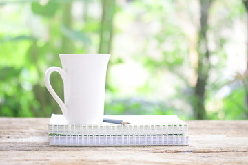 Notebook  and  white cup on wooden table