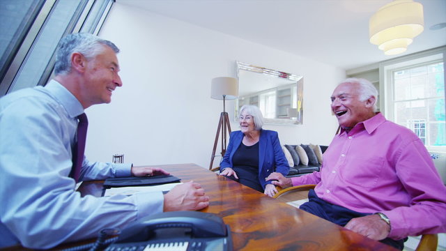 Cheerful senior couple in discussion with their financial advisor.
