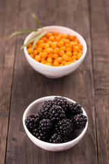 Blackberries and sea buckthorn on wooden table