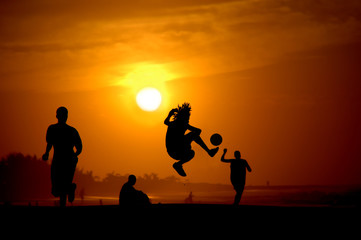 Fototapeta na wymiar Jóvenes jugando al futbol en la playa