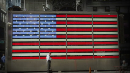 A man stands in front of an electronic representation of the American flag