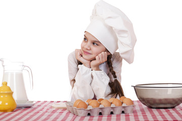 Little girl in a white apron near the box with eggs